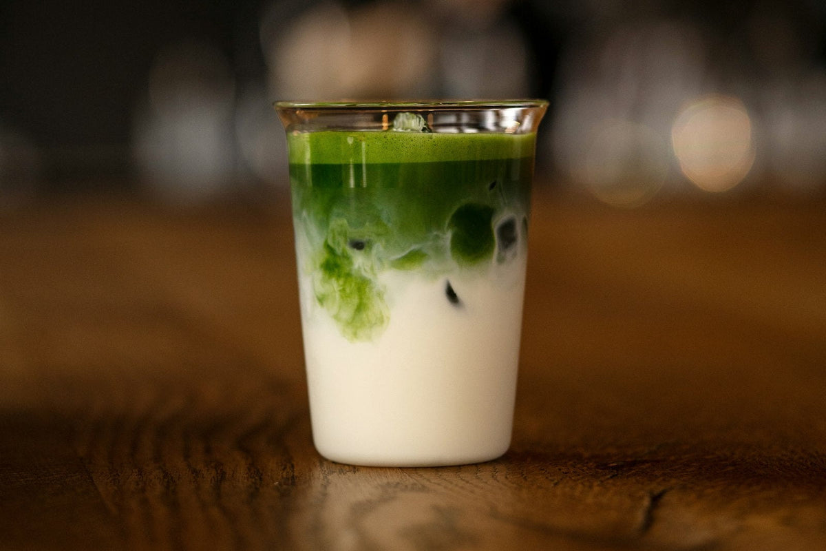 Iced matcha latte made at home, with green matcha layered over cold milk